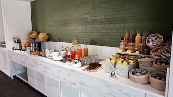 Ein Buffet mit verschiedenen Speisen und Getränken, darunter Obst, Säfte und Soßen.