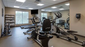 Un gimnasio con diversos equipos de ejercicio, incluyendo cintas de correr, elípticas y mancuernas.