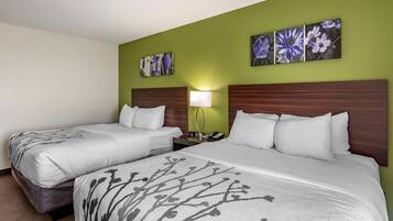 A hotel room with two beds, a nightstand, and a wall-mounted lamp.