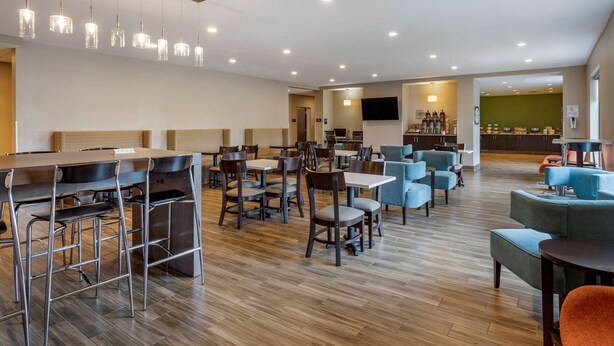 Un vestíbulo de hotel amplio con una larga recepción, varias zonas de estar y un bar.
