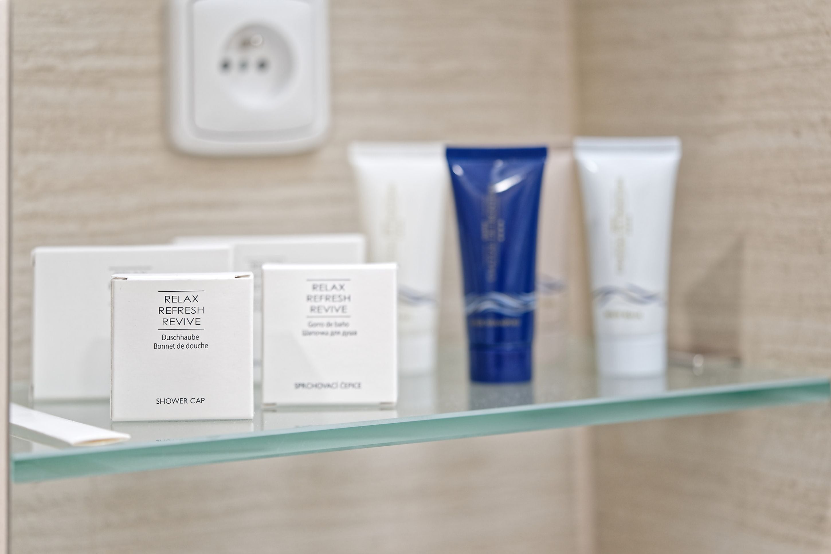 A bathroom with a glass shelf displaying various toiletries.