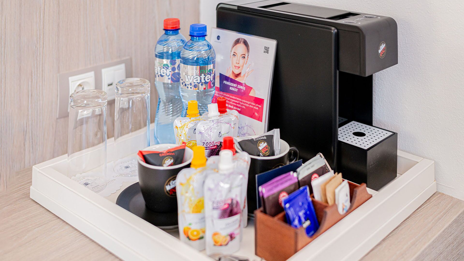A self-service beverage station with water bottles, juice, and a coffee machine.