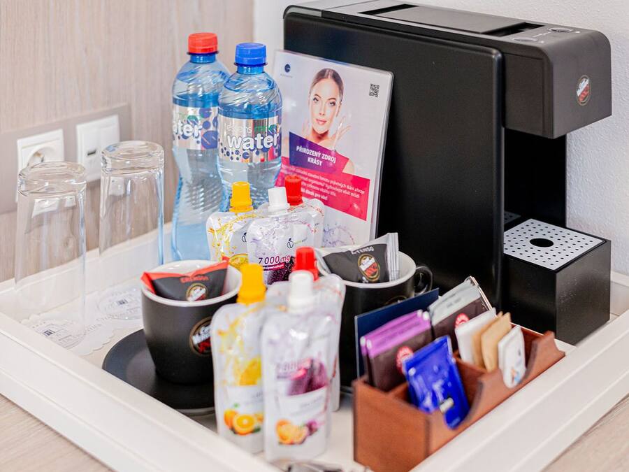 A self-service beverage station with water bottles, juice, and a coffee machine.