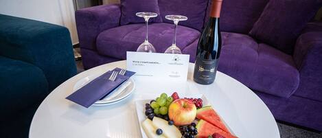 Una mesa de comedor con un plato de fruta, una botella de vino y una tarjeta de menú.