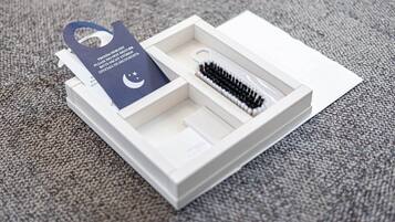 Une boîte blanche contenant un pinceau noir et blanc, une étiquette bleue avec du texte et une carte blanche.