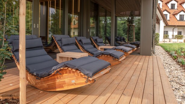 A covered outdoor lounge area with wooden loungers and a wooden deck. - Hraniční zámeček (Lednice)