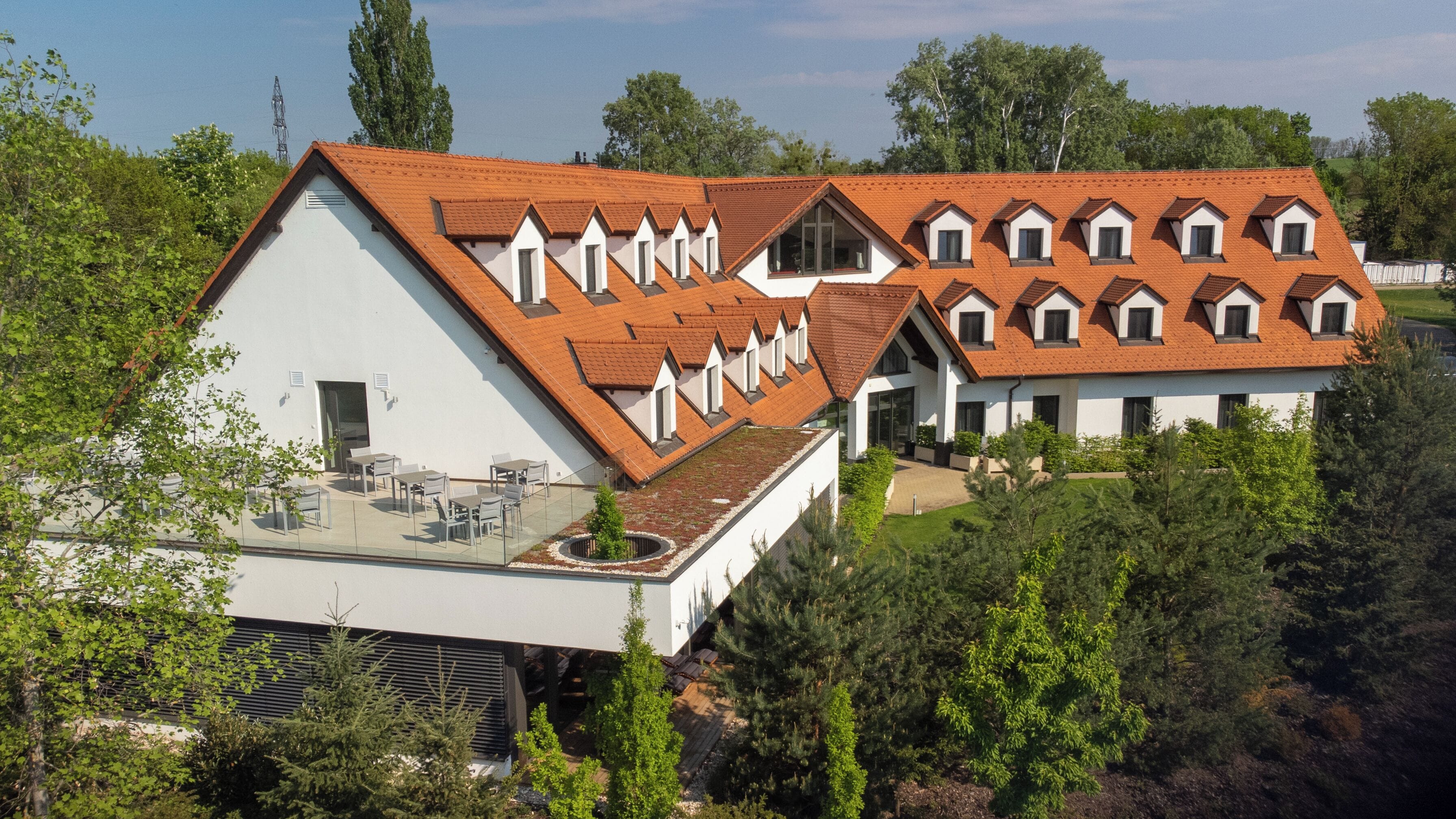A modern house with a sloped roof, multiple dormer windows, and a covered patio area.