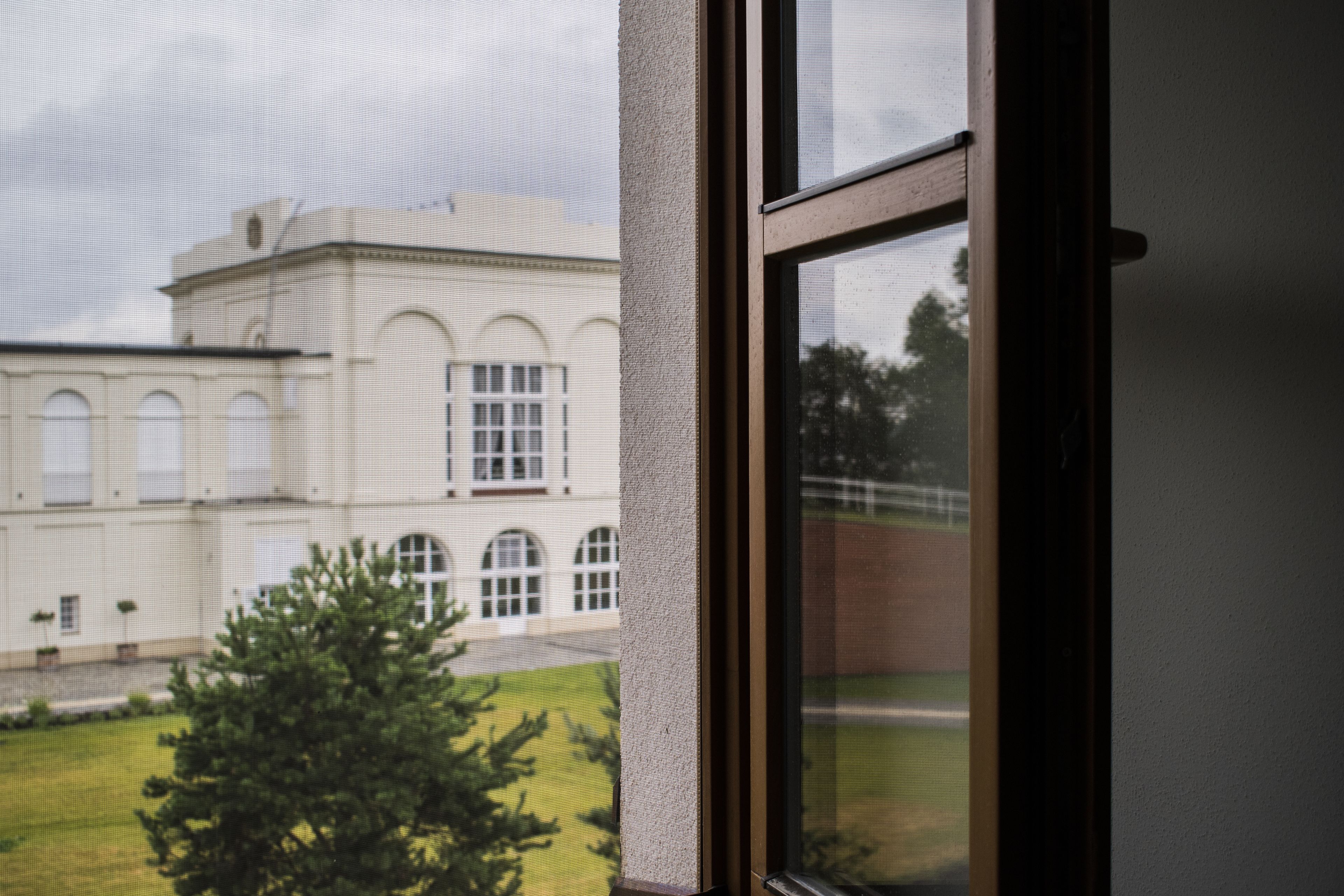 A view through a window of a building with arched windows and a symmetrical facade.