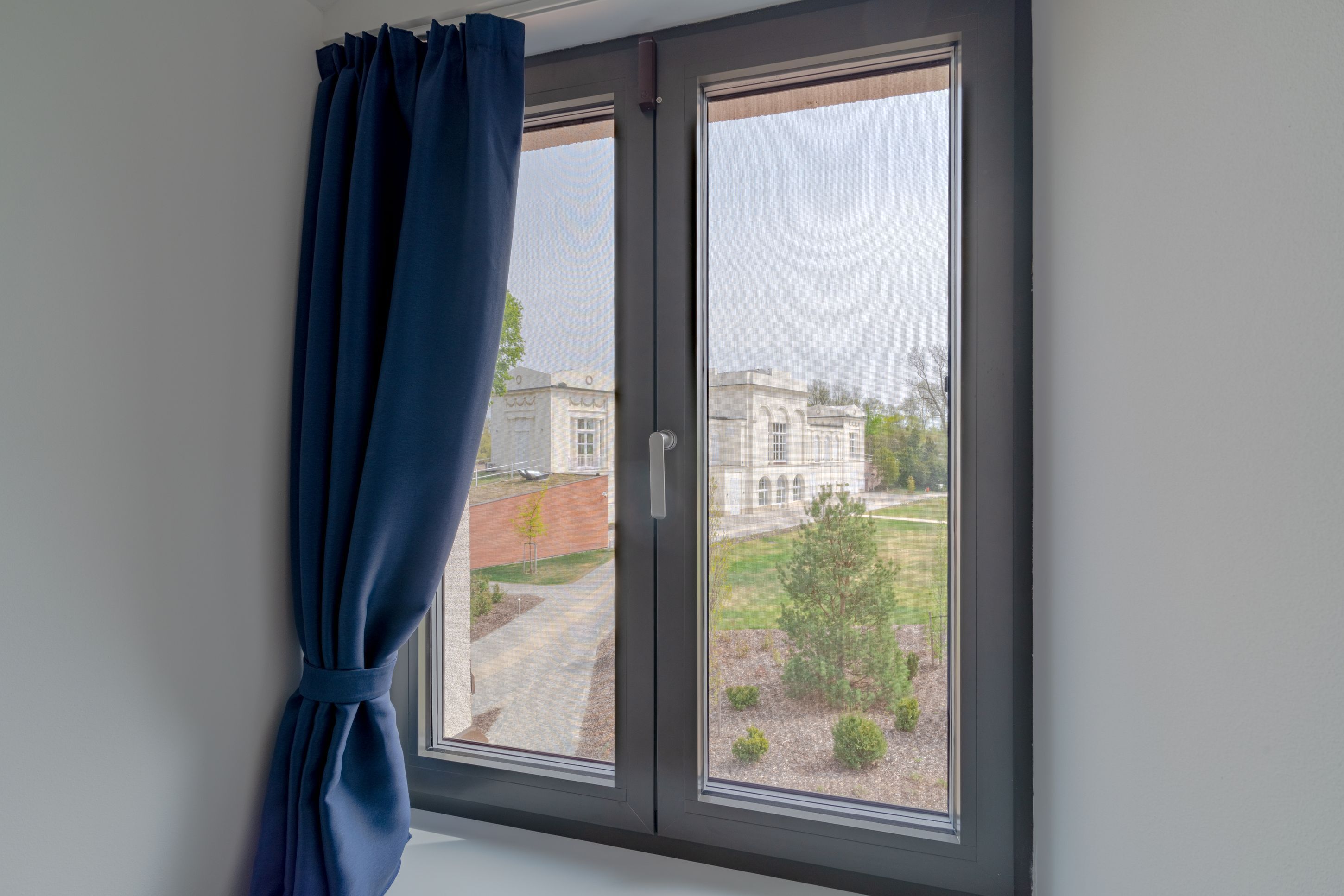 Ein Fenster mit Blick auf ein Gebäude und einen klaren Himmel.