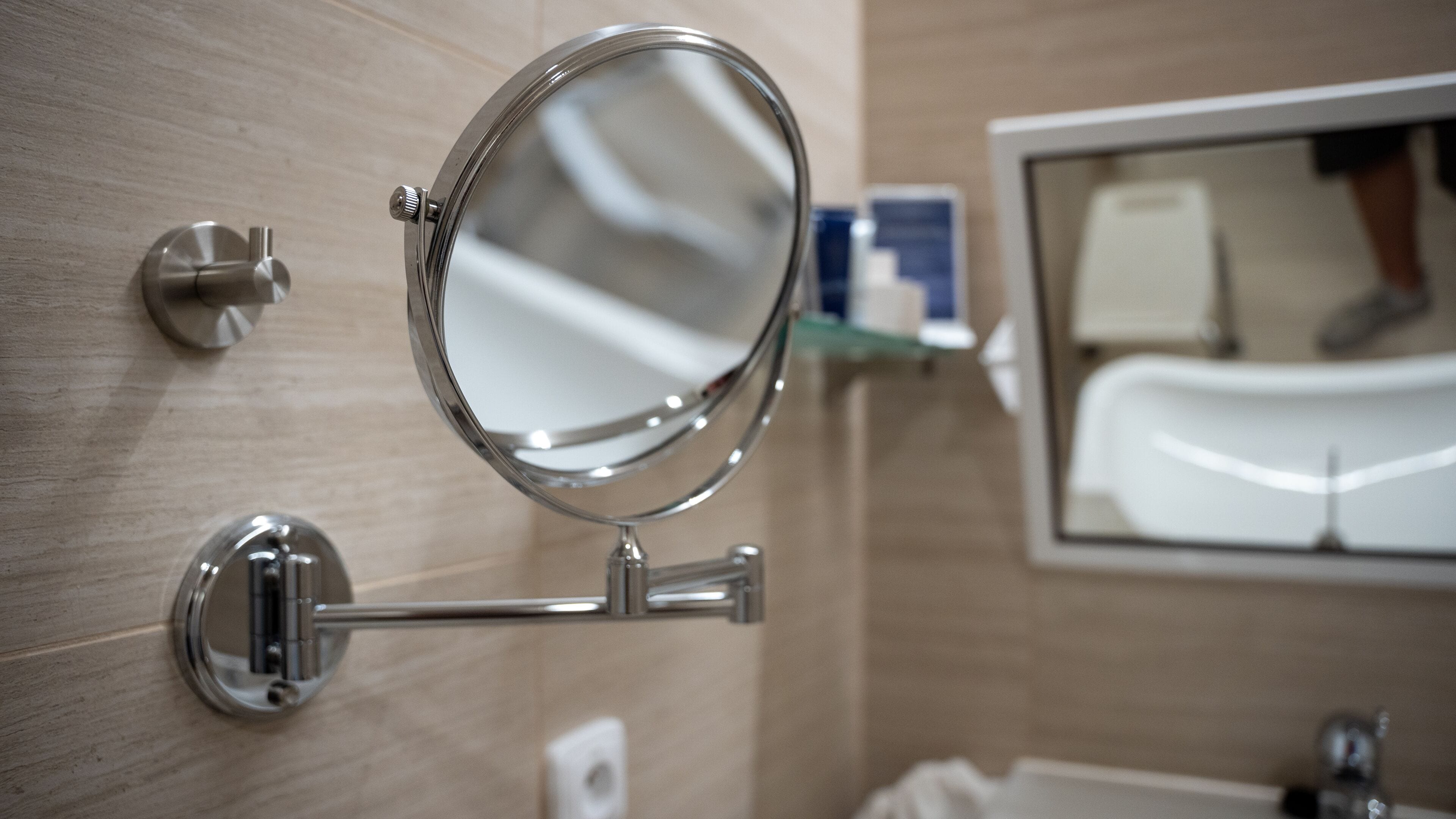 A bathroom with a wall-mounted mirror, a sink, and a towel rack.