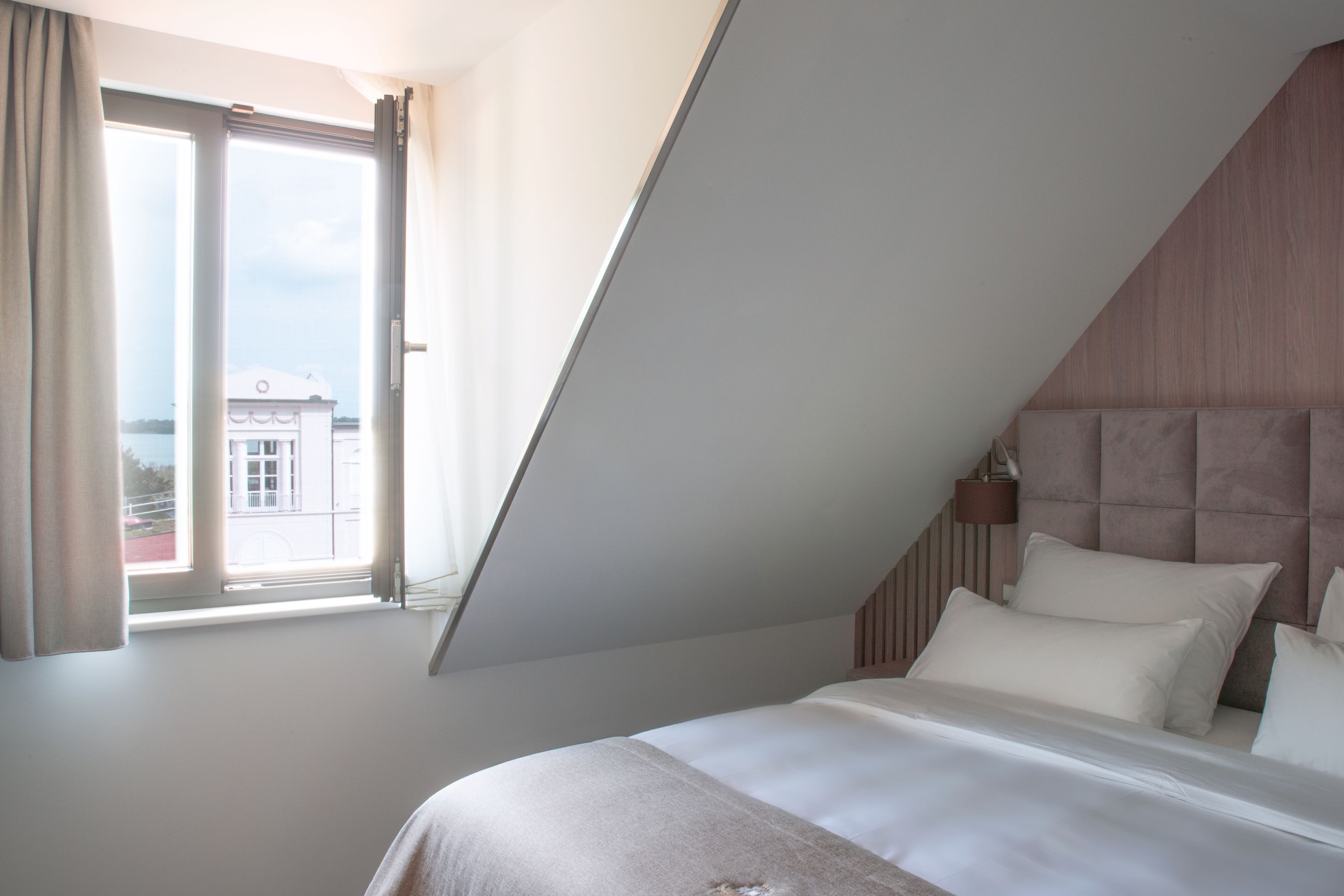 Un dormitorio con una cama grande, cabecera y una ventana con cortinas.