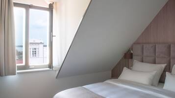 Un dormitorio con una cama grande, cabecera y una ventana con cortinas.