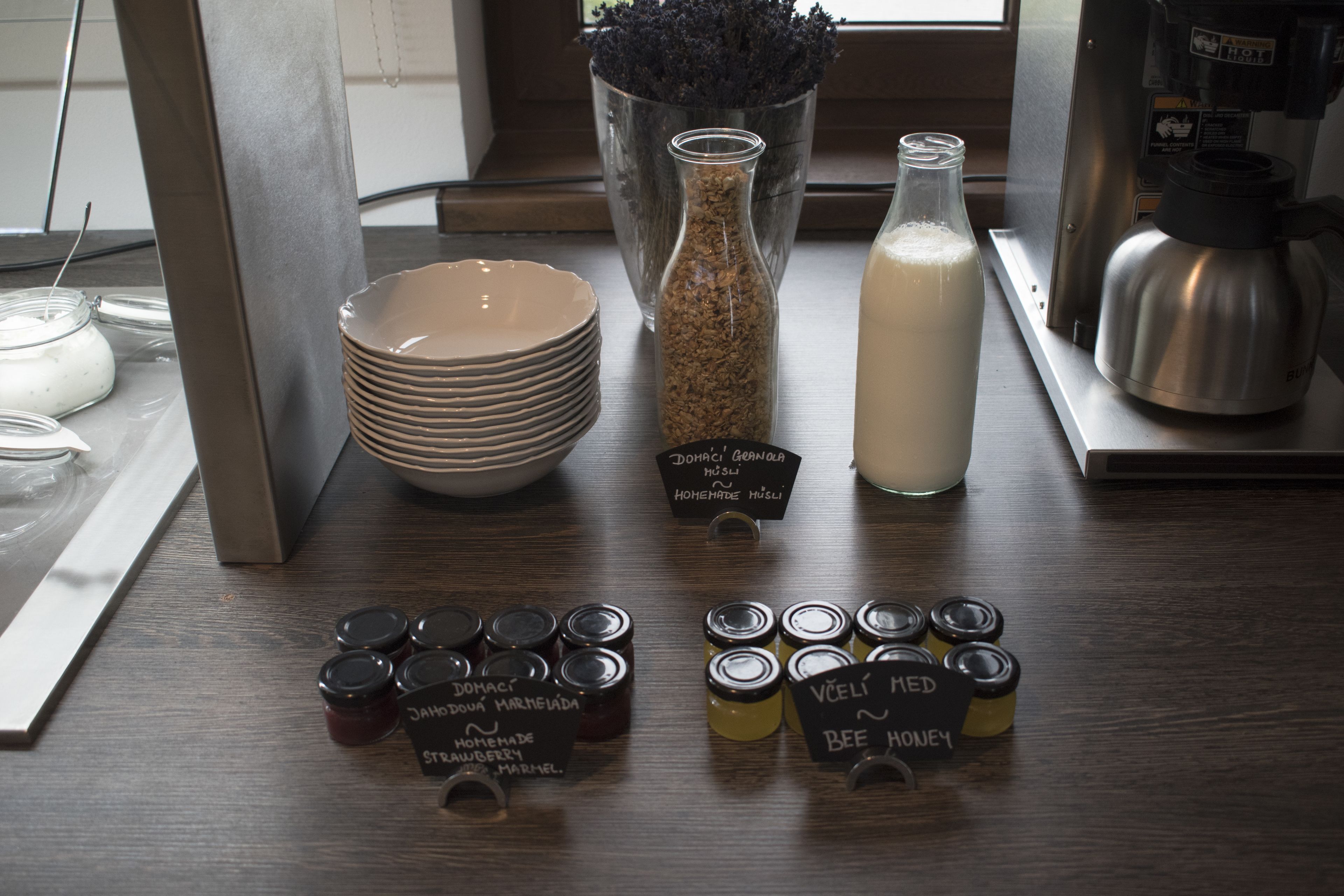 A table with various jars of honey and a bottle of milk.