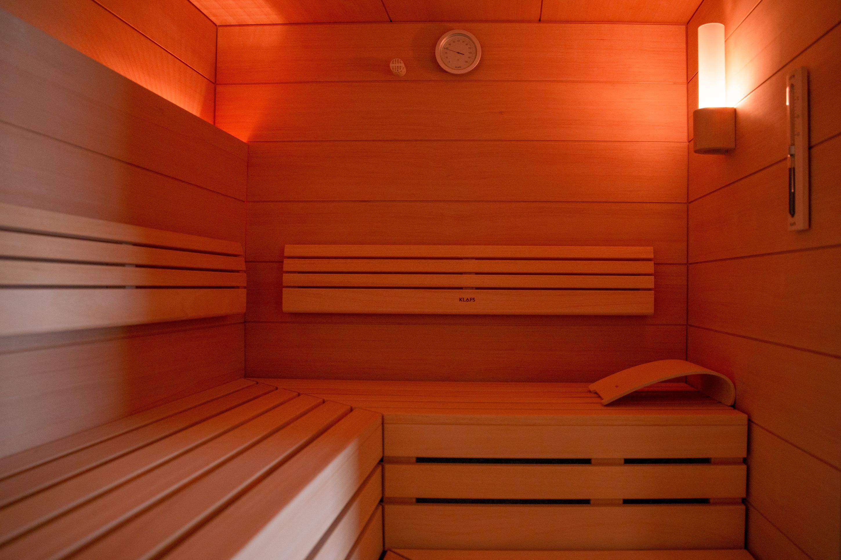 A sauna with wooden benches and a wall-mounted heater.