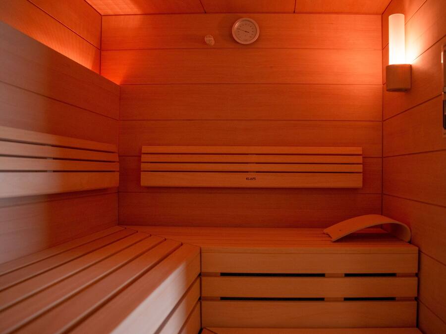 A sauna with wooden benches and a wall-mounted heater.