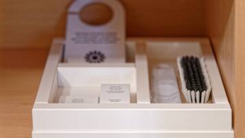 A white shoe shine kit with a brush, sponge, and a label inside a wooden drawer.