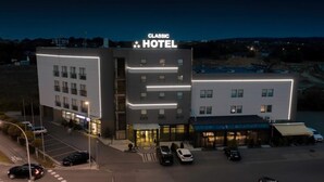 A multi-story hotel with a prominent "Classic Hotel" sign. The building features a modern design with illuminated lines and a parking lot in front. - Hotel Classic (Rzeszów)