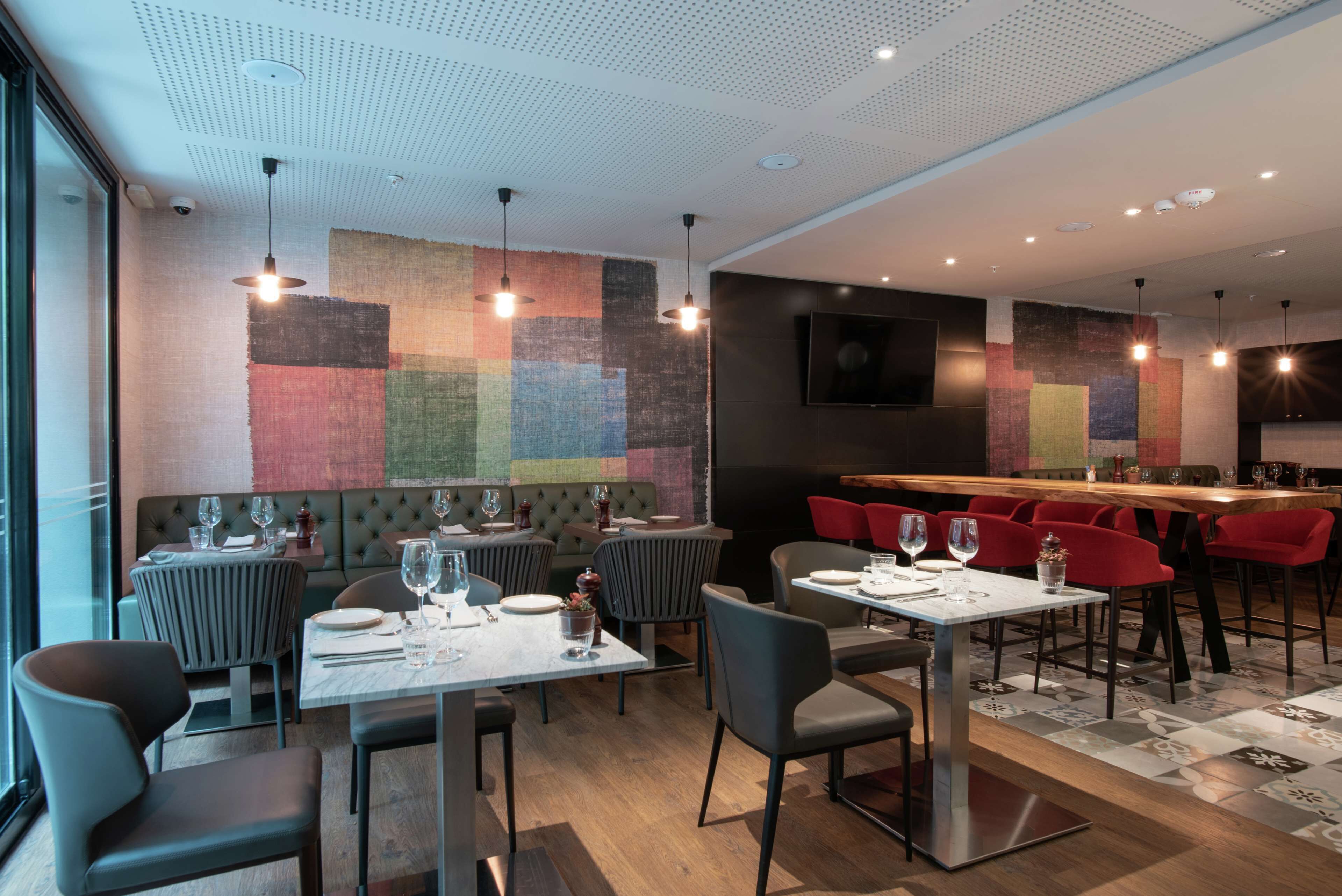 Un restaurante moderno con barra, mesas con cabinas y taburetes altos.