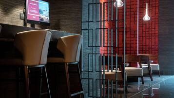 Zona de bar moderna con taburetes altos, un televisor de pantalla plana y lámparas de diseño contemporáneo.