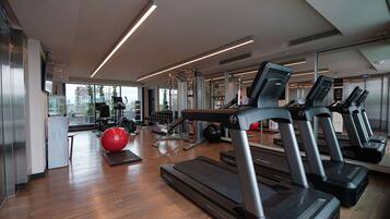 Un gimnasio moderno con cintas de correr, pelotas de ejercicio y máquinas de pesas.