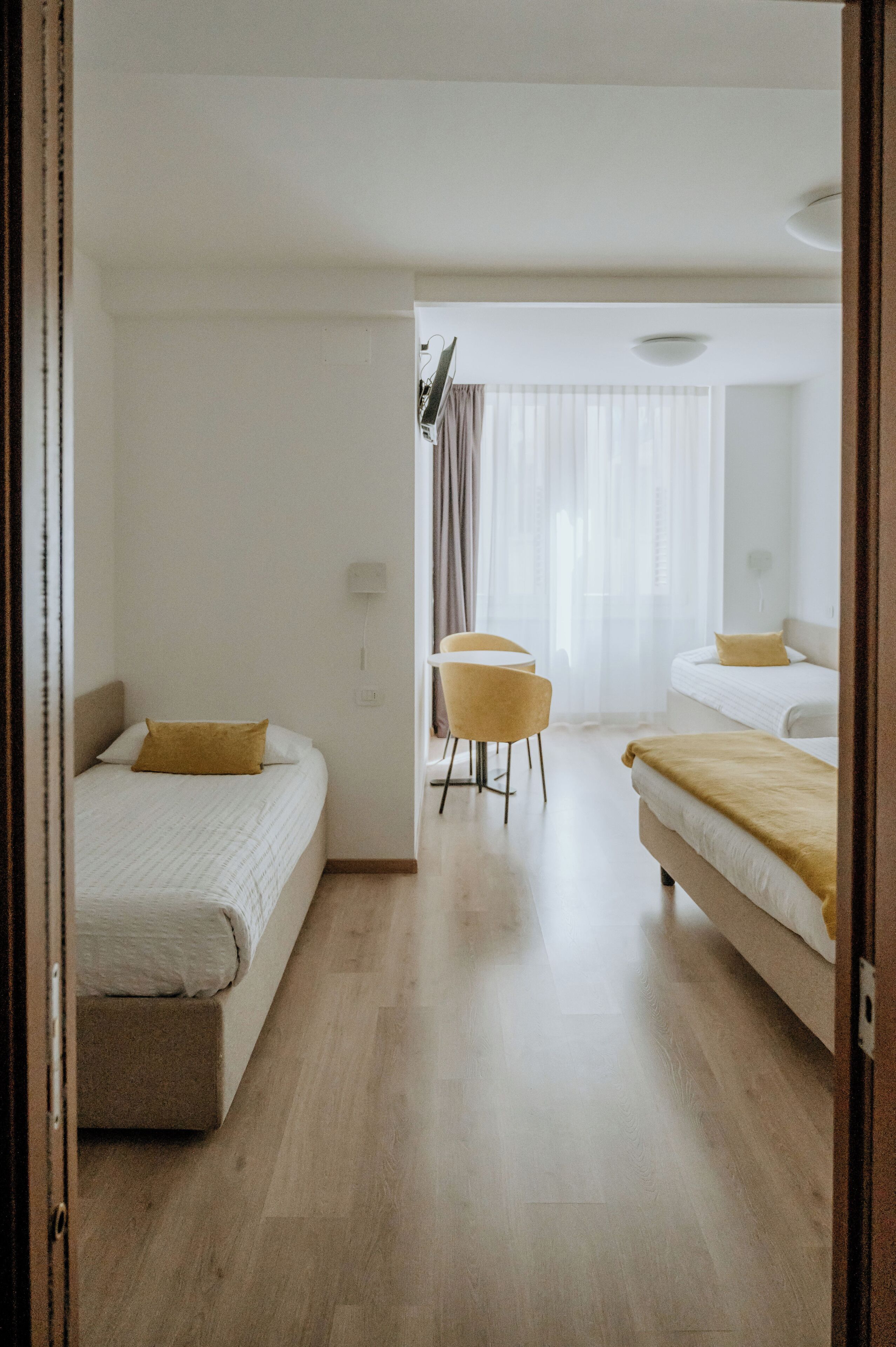 A hotel room with two beds, a small round table, and a chair.