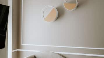 En beige sofa med buet ryg og to grønne puder.