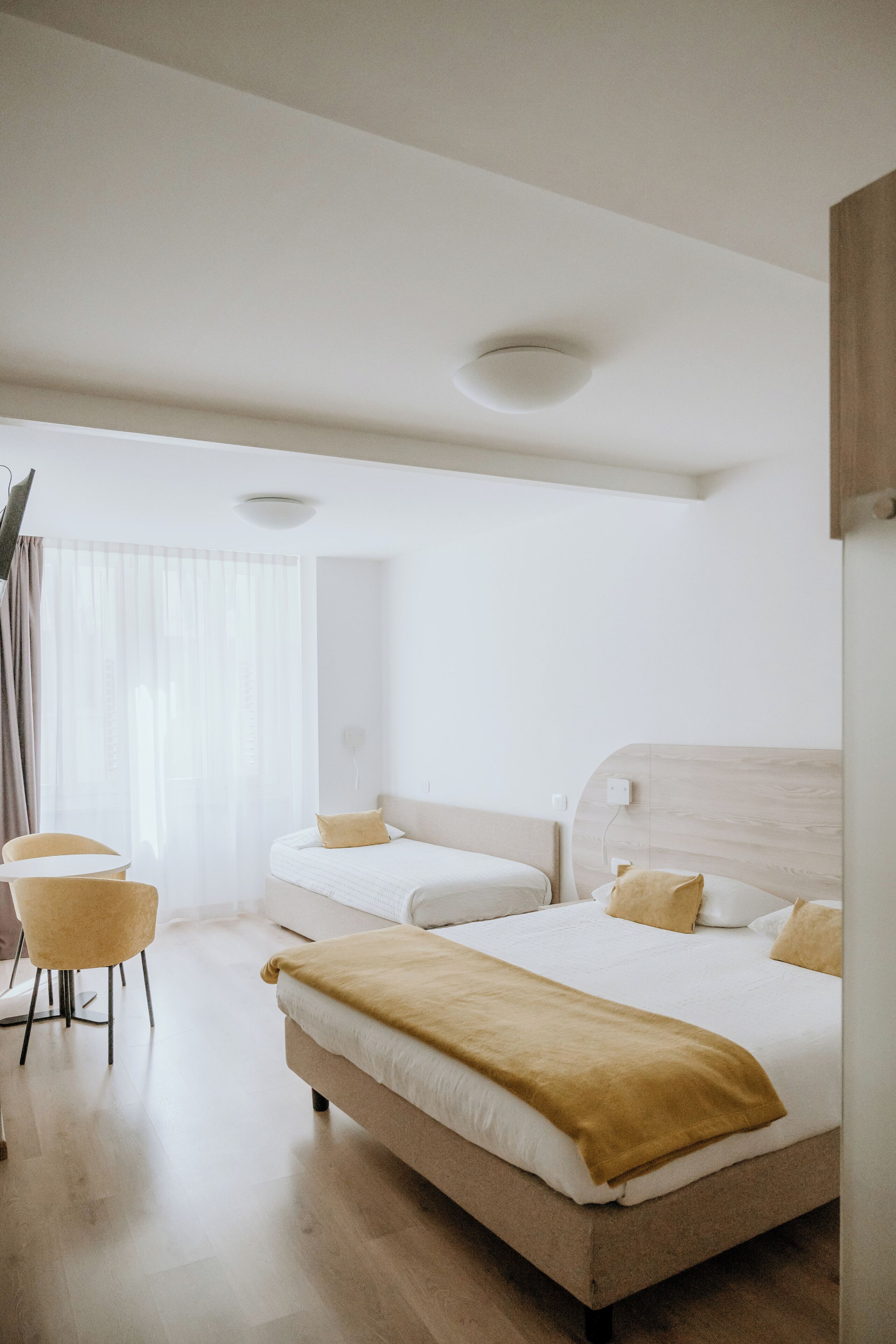 Een moderne hotelkamer met twee bedden, een zithoek met een stoel en een groot raam.