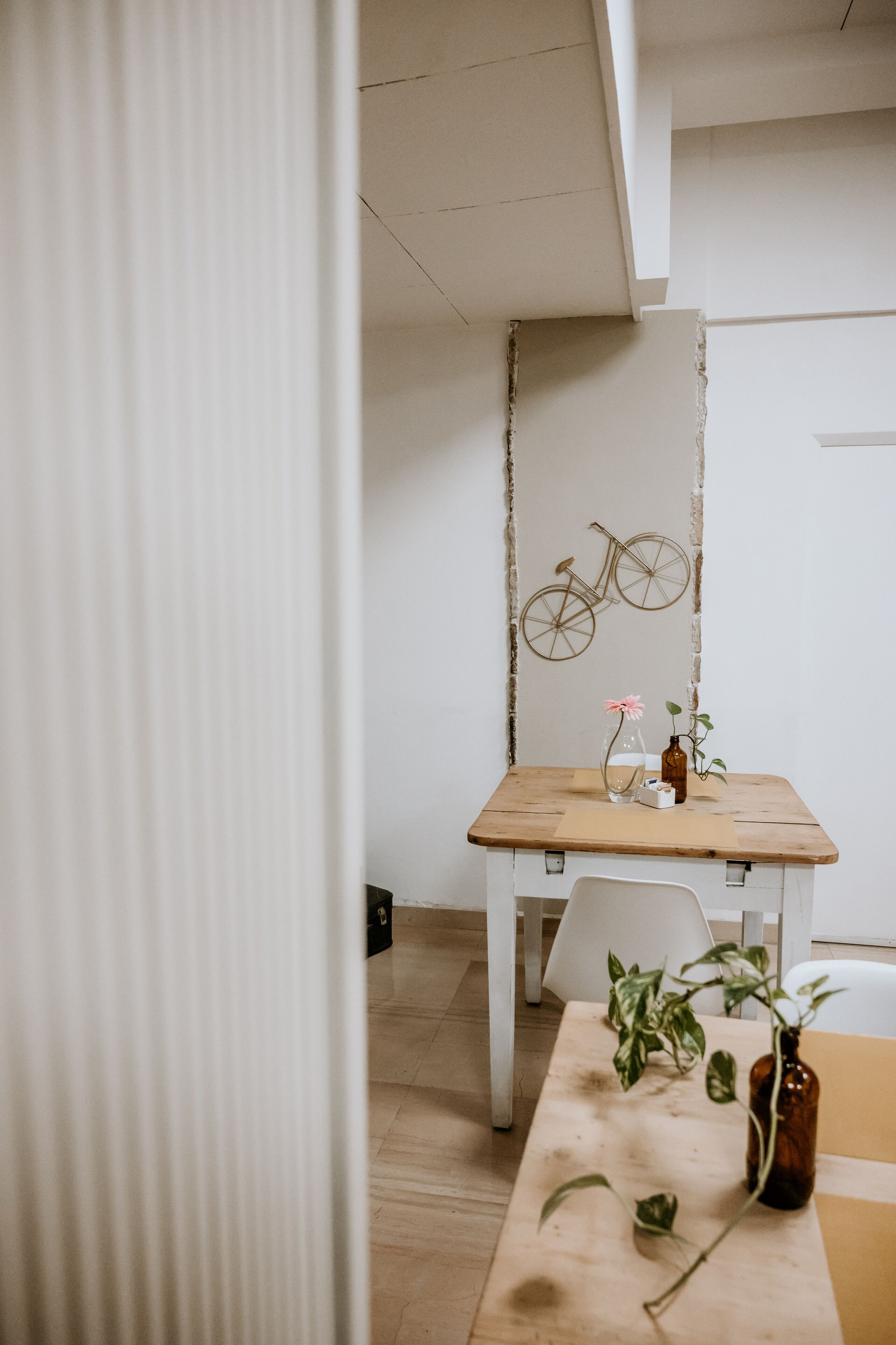 Un comedor minimalista con una mesa de madera, sillas blancas y una bicicleta decorativa en la pared.
