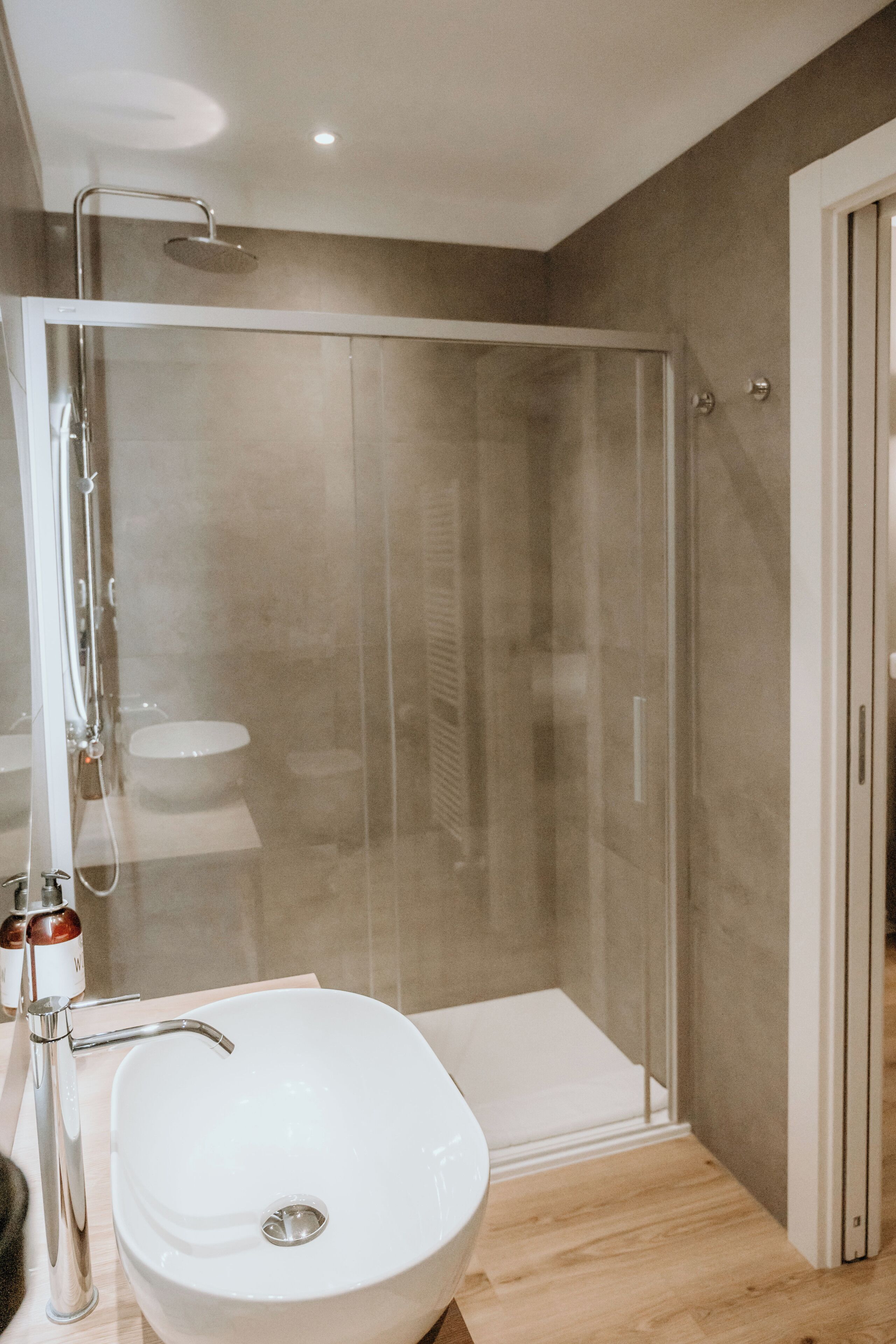 A modern bathroom with a glass-enclosed shower, a white sink, and a toilet.