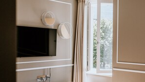 Ein modernes Badezimmer mit einer freistehenden Badewanne, einem runden Spiegel und einem an der Wand befestigten Fernseher.
