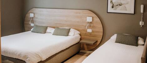 A bedroom with two beds, wooden beams on the ceiling, a wall-mounted phone, and a framed abstract painting.