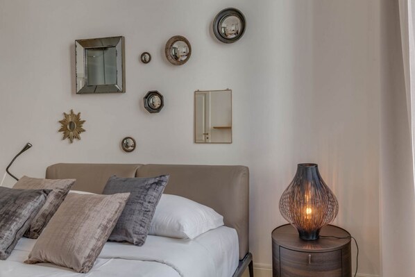A bedroom with a bed, bedside table, and wall-mounted mirrors.