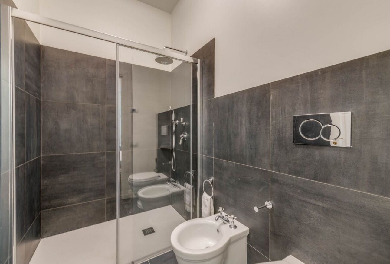 A modern bathroom with a glass shower enclosure, a sink, and a mirror.