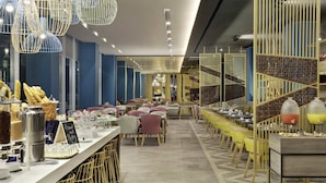 A modern restaurant with a long counter, multiple seating areas, and decorative lighting.