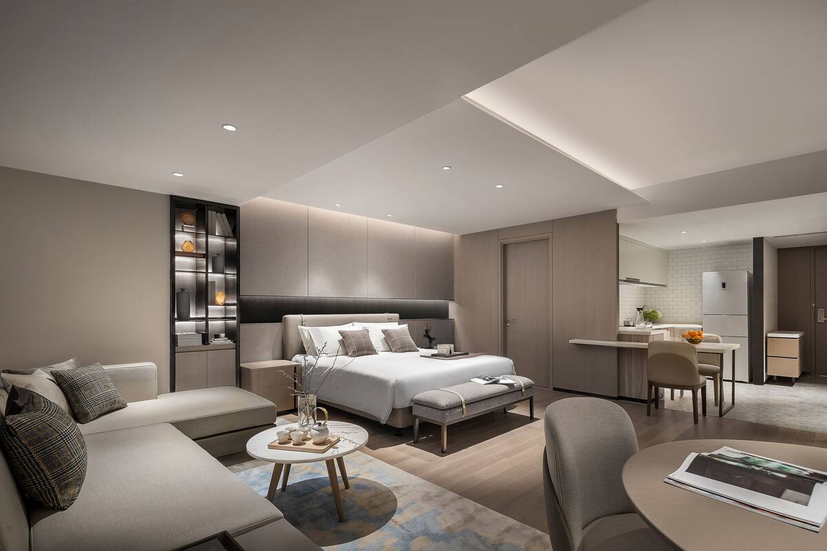 Une chambre moderne avec un grand lit, des tables de chevet, un canapé et un coin repas.