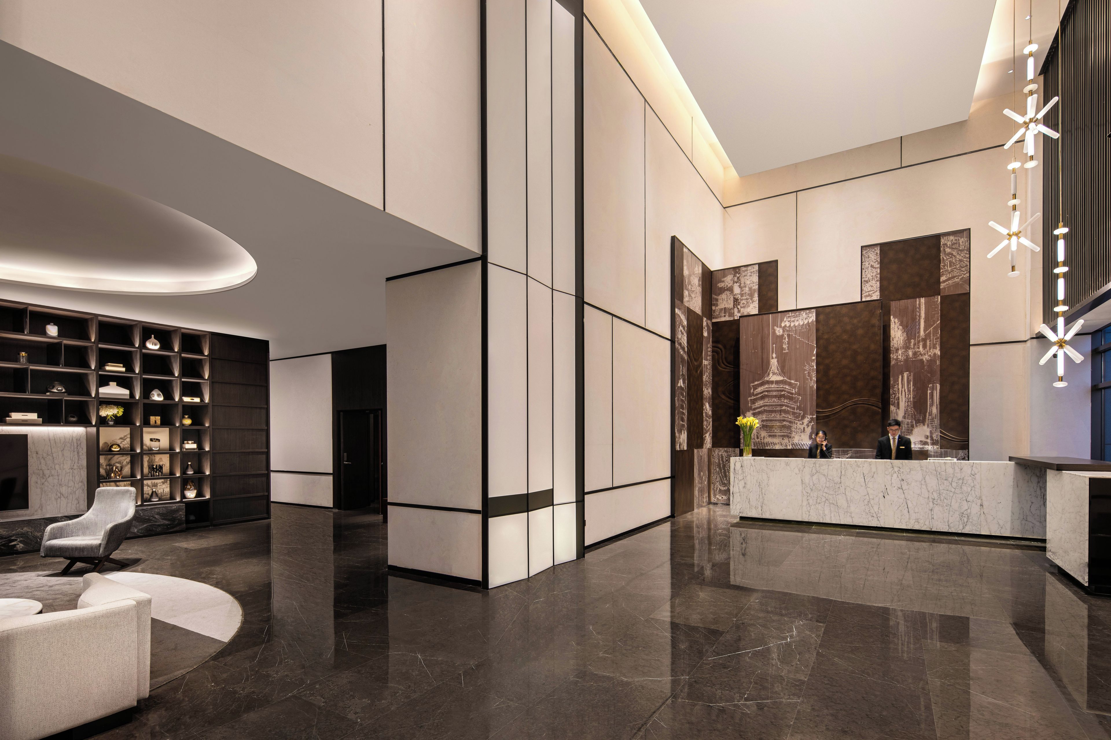 Um lobby moderno com balcão de recepção, área de estar e uma parede com obras de arte.