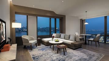 A modern living room with a sofa, chairs, a coffee table, and a view of the cityscape.