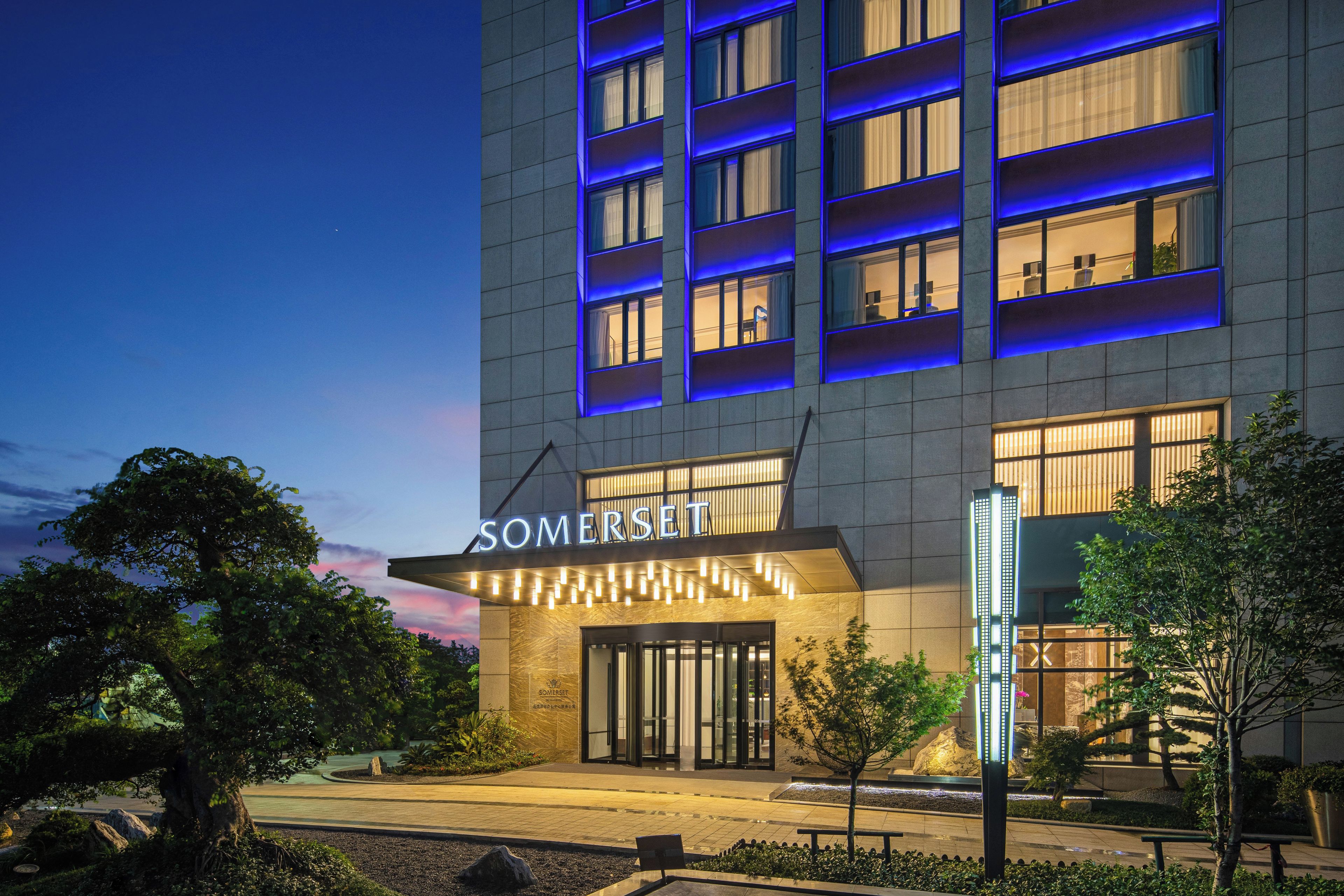 A modern hotel with a prominent entrance, multiple floors, and illuminated signage.