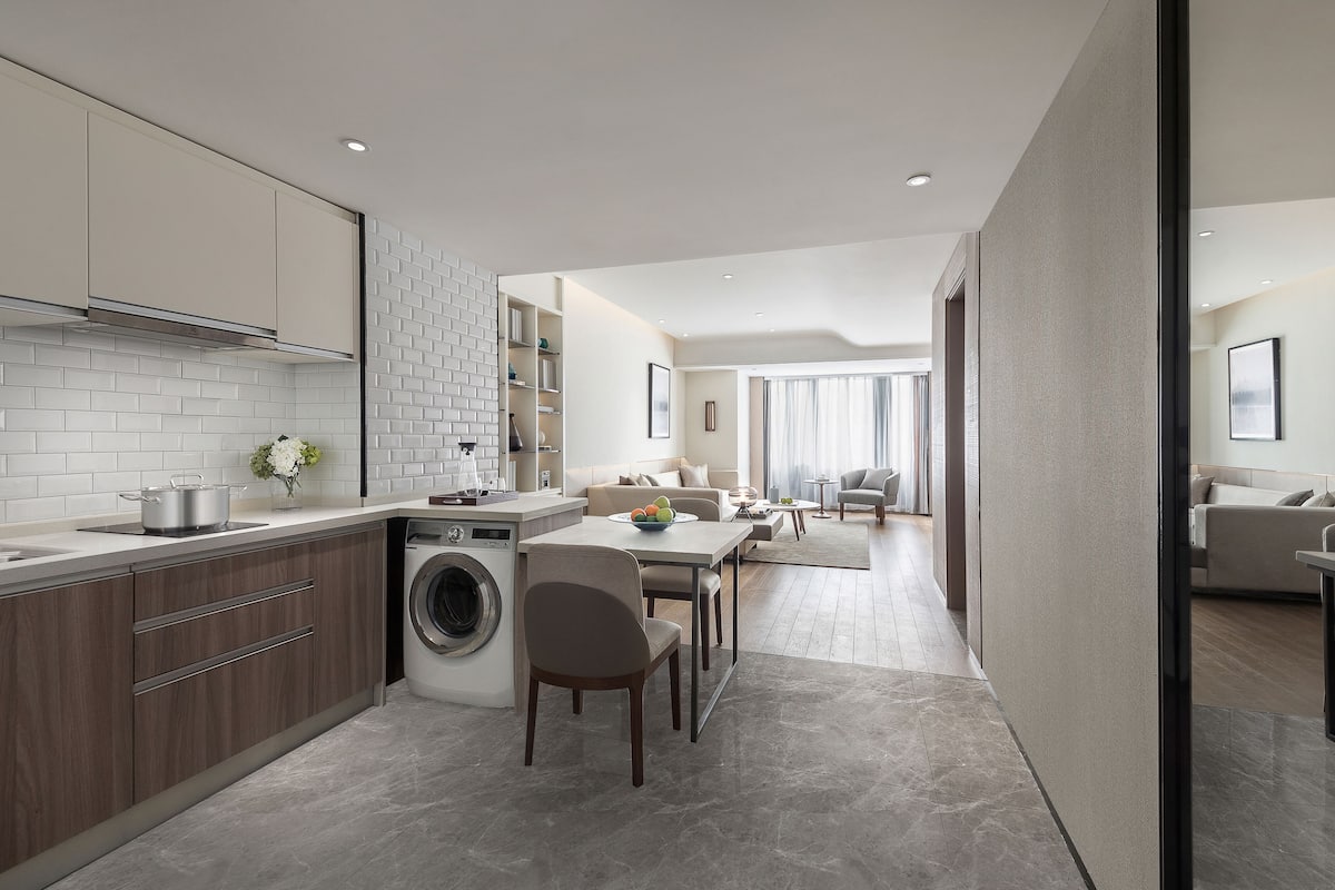 Une cuisine moderne équipée d’un lave-linge intégré, un coin repas avec une table et des chaises, et un salon avec un canapé et une table basse.