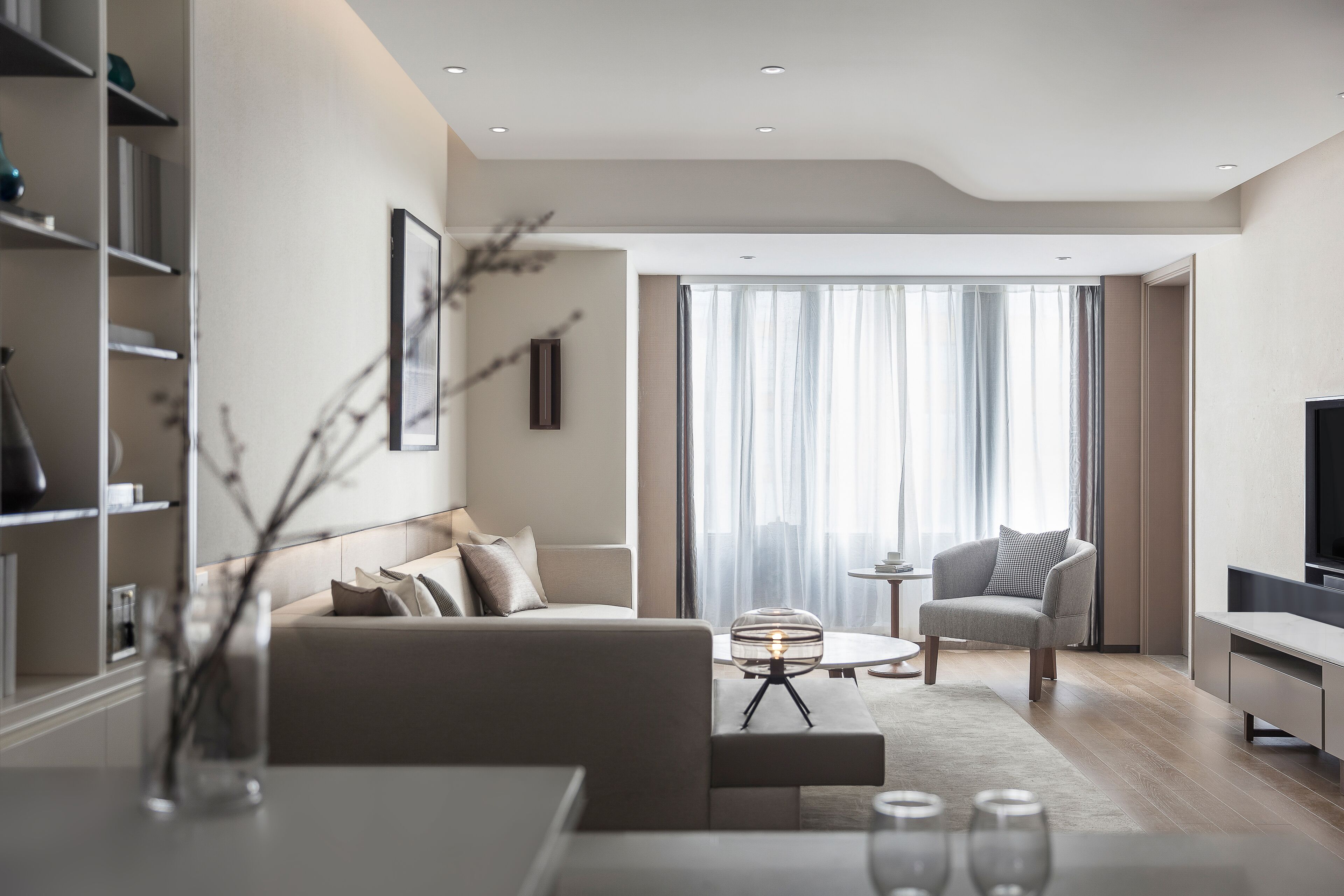 Ein modernes Wohnzimmer mit Sofa, Sessel, Couchtisch und Fernseher.
