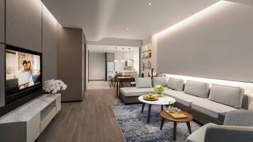 A modern living room with a flat-screen TV, a sofa, a coffee table, and a dining area in the background.