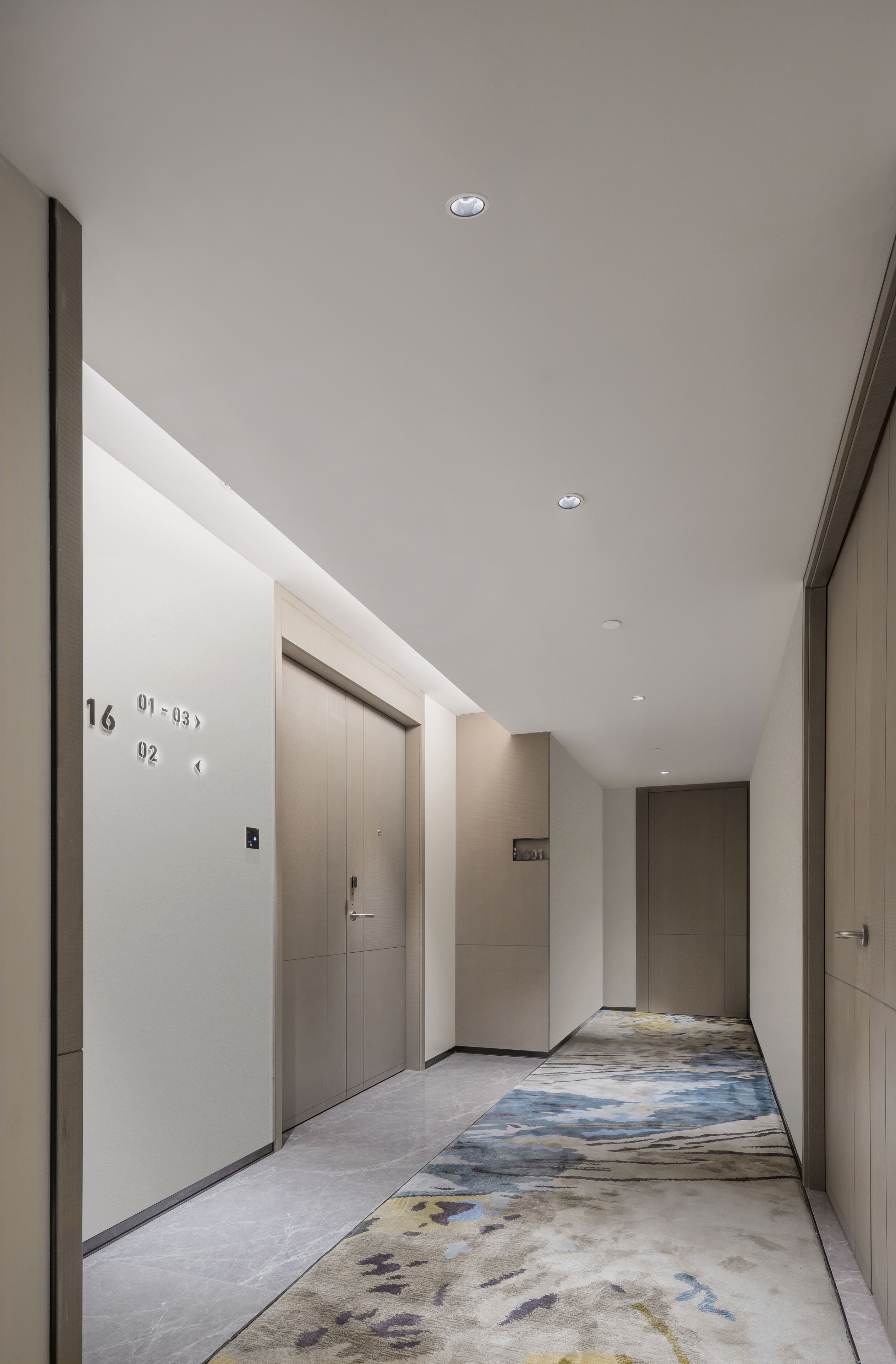 A modern hallway with numbered doors, a patterned carpet, and recessed ceiling lighting.