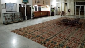 Un hall d’entrée spacieux, doté d’un tapis à motifs, d’un comptoir de réception et d’une vitrine exposant des objets d’art.