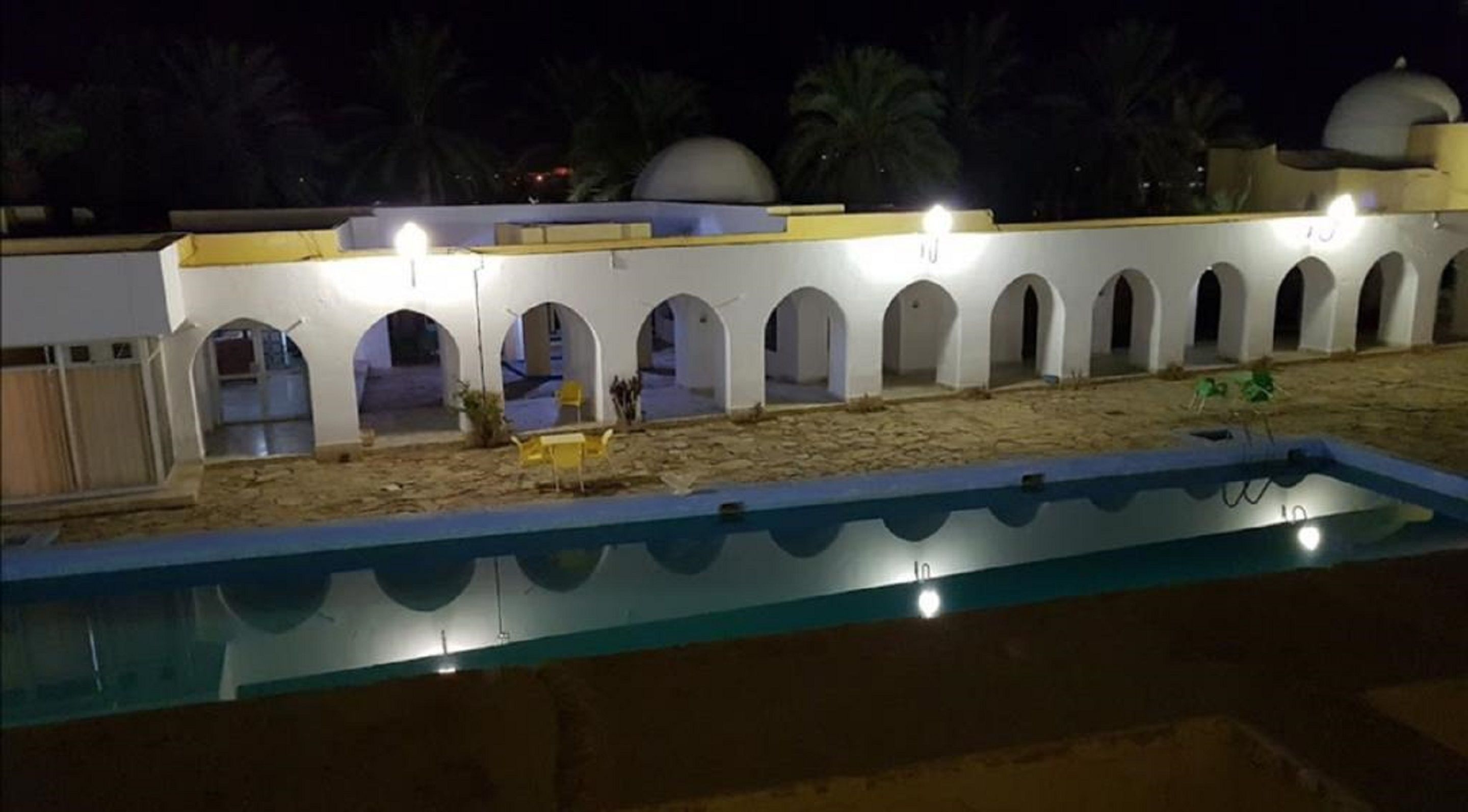 Een buitenzwembad, parasols bij het zwembad en ligstoelen