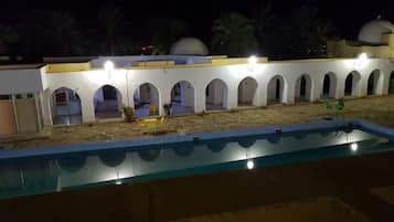 Een buitenzwembad, parasols bij het zwembad en ligstoelen