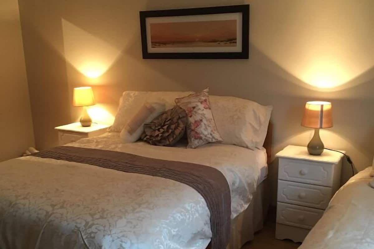 Une chambre avec deux lits, un tableau encadré au mur et des lampes de chevet.