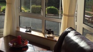 Een kamer met een groot raam, een leren bank en een klein tafeltje met een kaars en een beeldje.