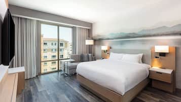 Een hotelkamer met een groot bed, een bureau en uitzicht op een gebouw.