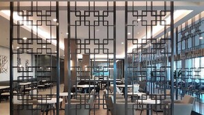 A modern interior with a geometric partition, seating areas, and a view of a cityscape through large windows. - Courtyard by Marriott Los Angeles Monterey Park (Monterey Park)