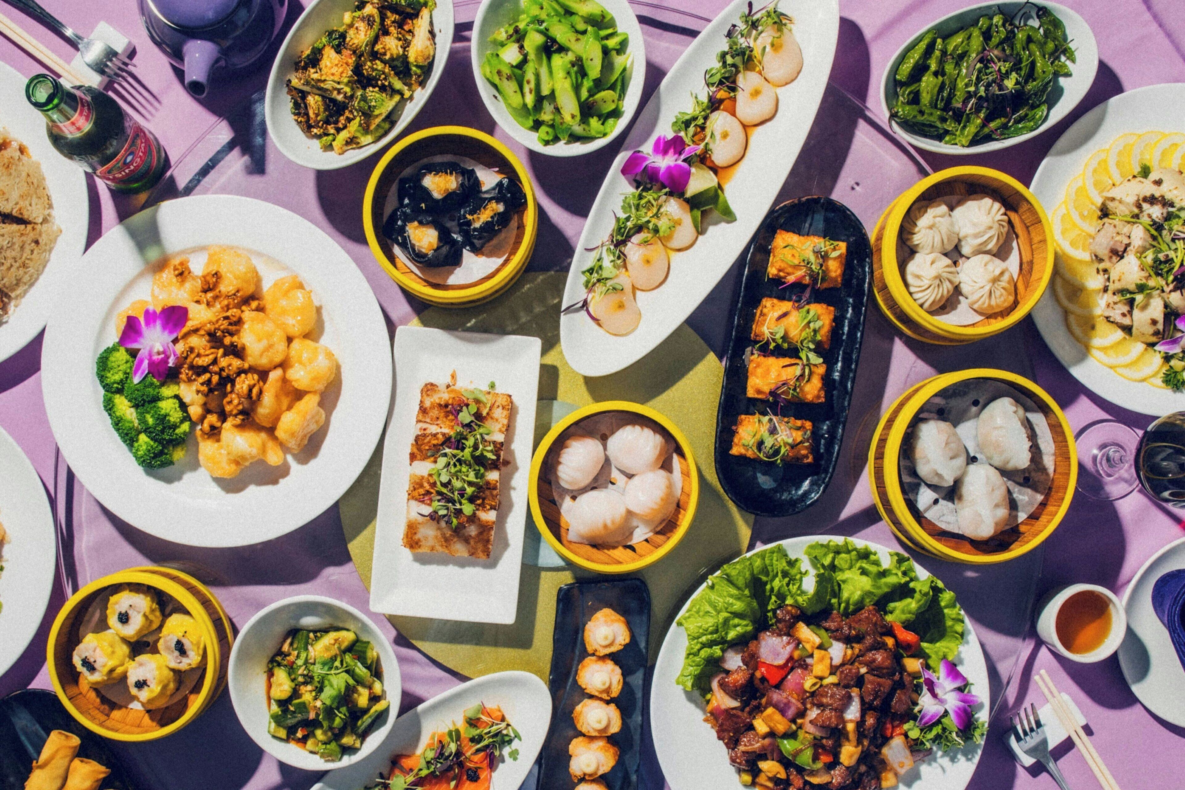 Una variedad de platos dispuestos en una mesa, incluyendo dumplings, ensaladas y guisos de carne.